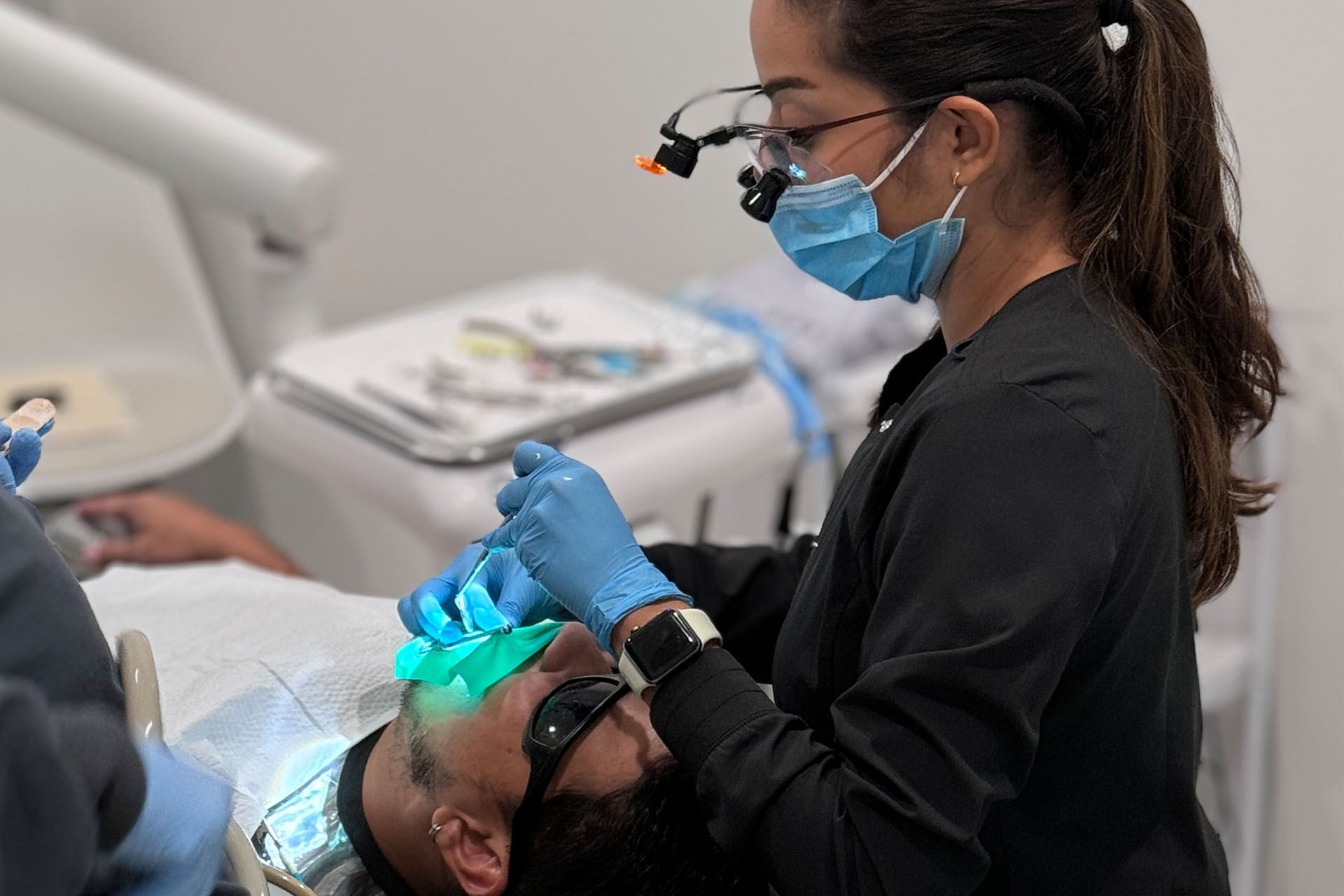A woman is working on a man's teeth in a dental office.