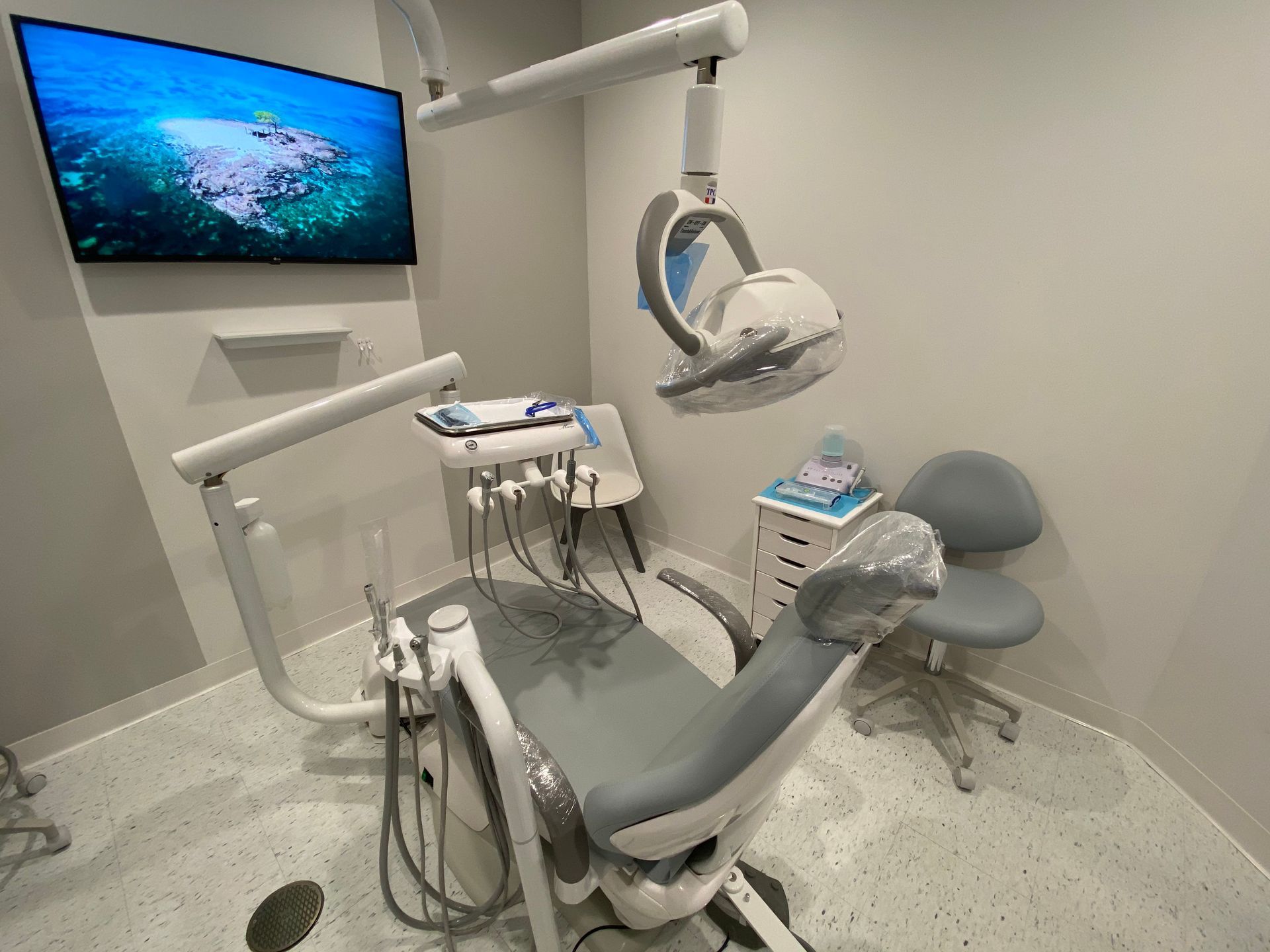A dental office with a dental chair and a television on the wall.