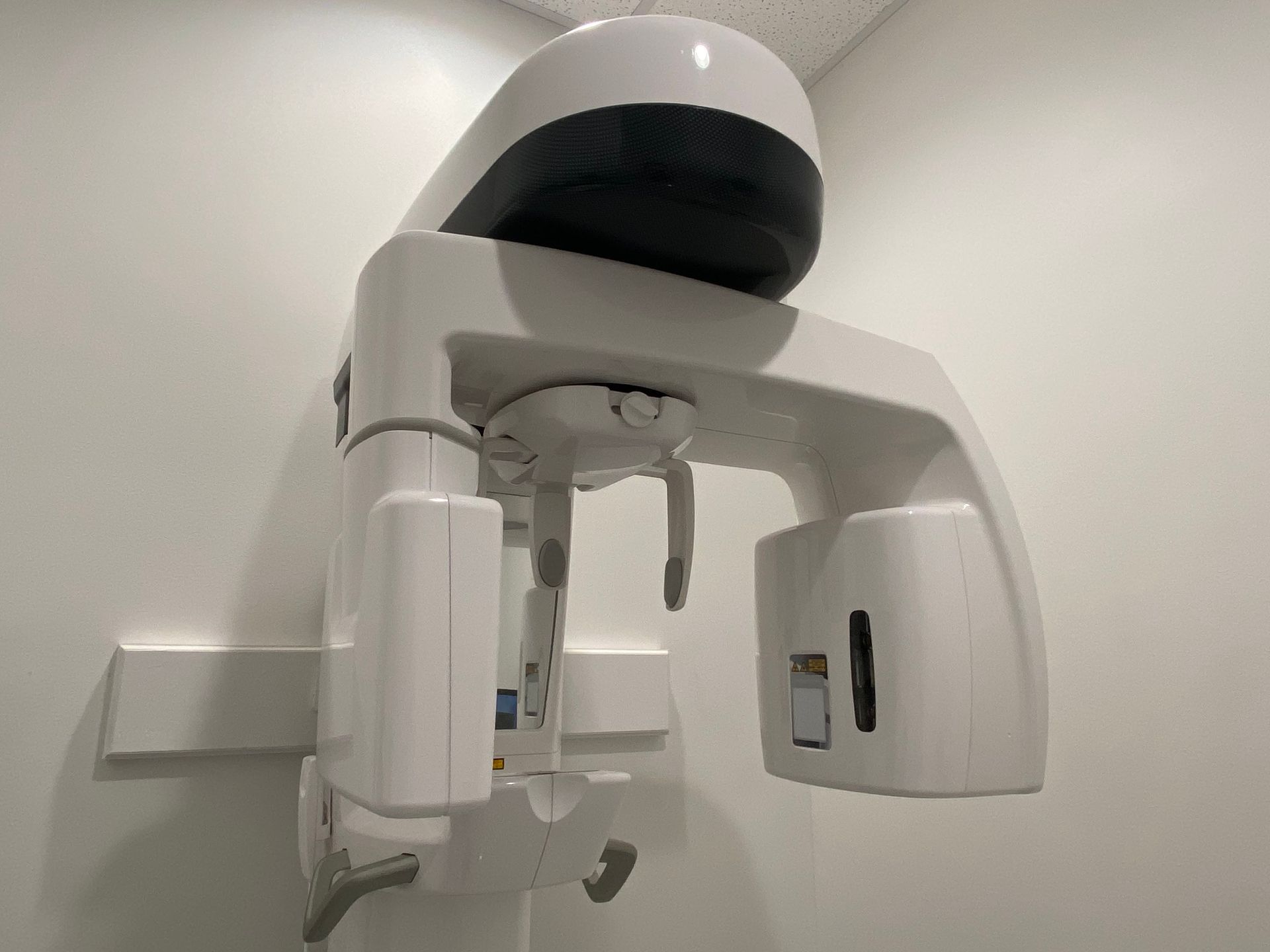 A dental x-ray machine is hanging from the ceiling in a dental office.