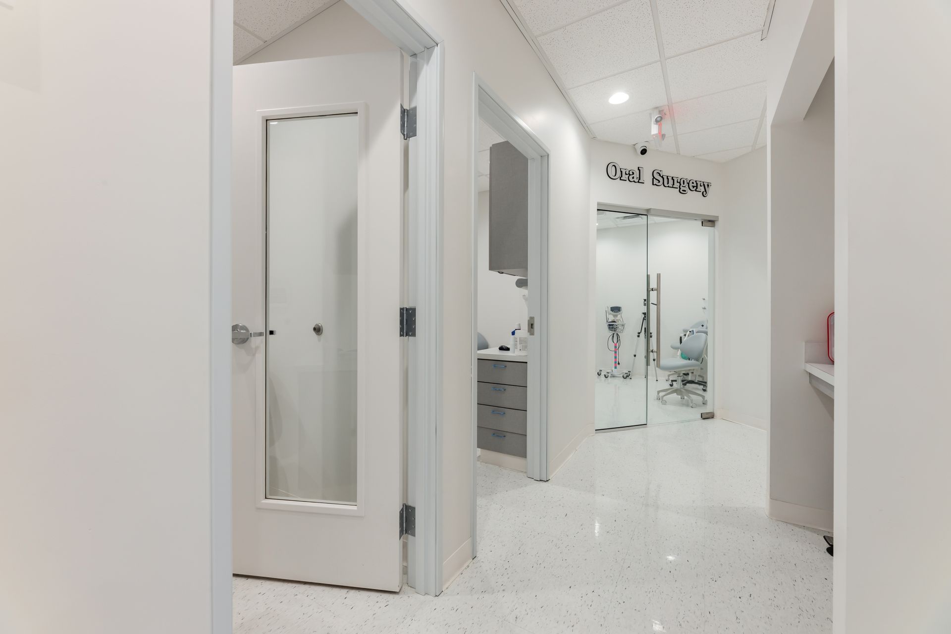 A hallway with white walls and a glass door leading to a dental office.