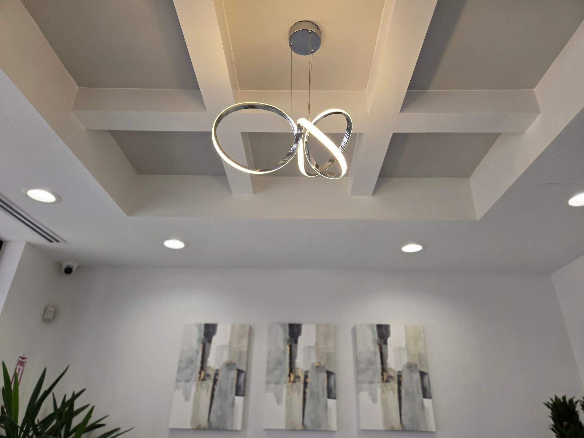 A ceiling with a light hanging from it and three paintings on the wall.