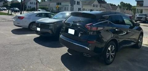 Parking lot with several parked cars, including a black SUV in the foreground.