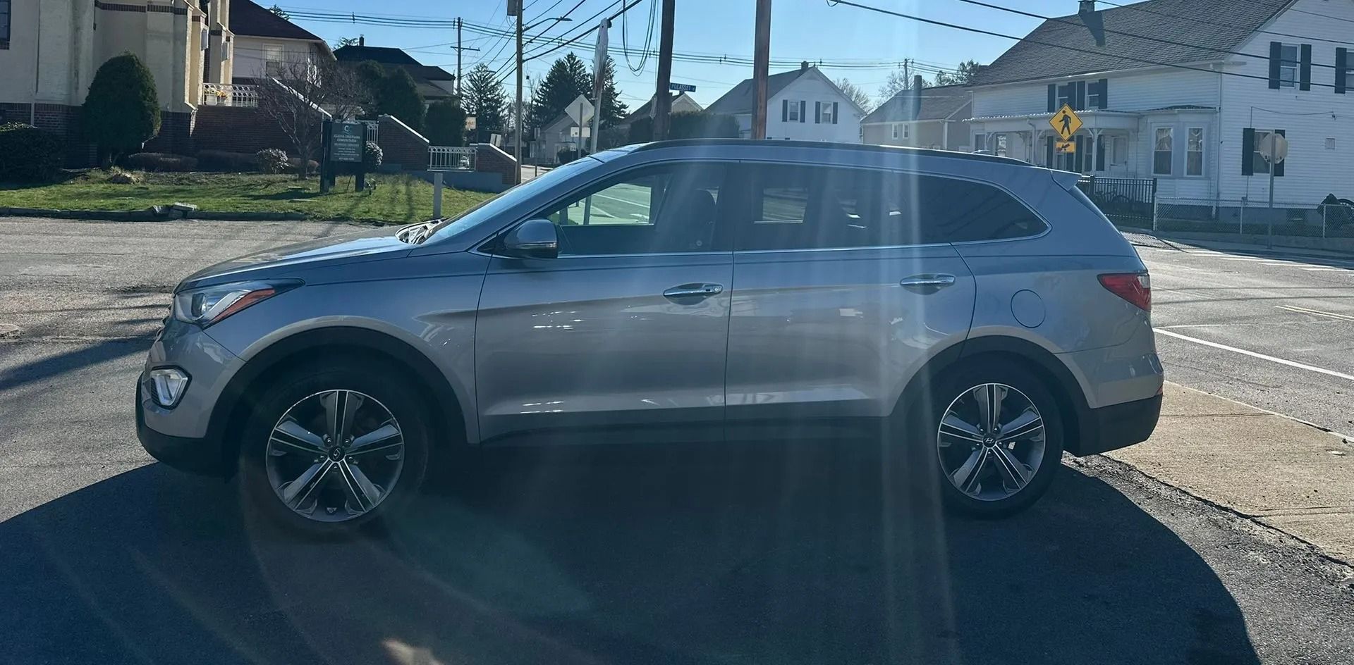 Silver SUV parked on a sunny residential street near houses and utility poles