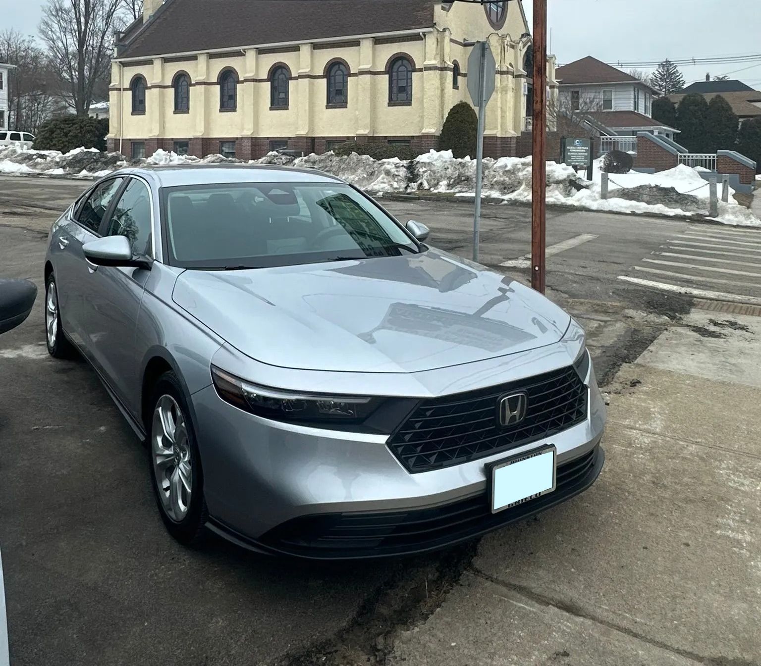 Silver sedan parked on a snowy residential street near a church-like building