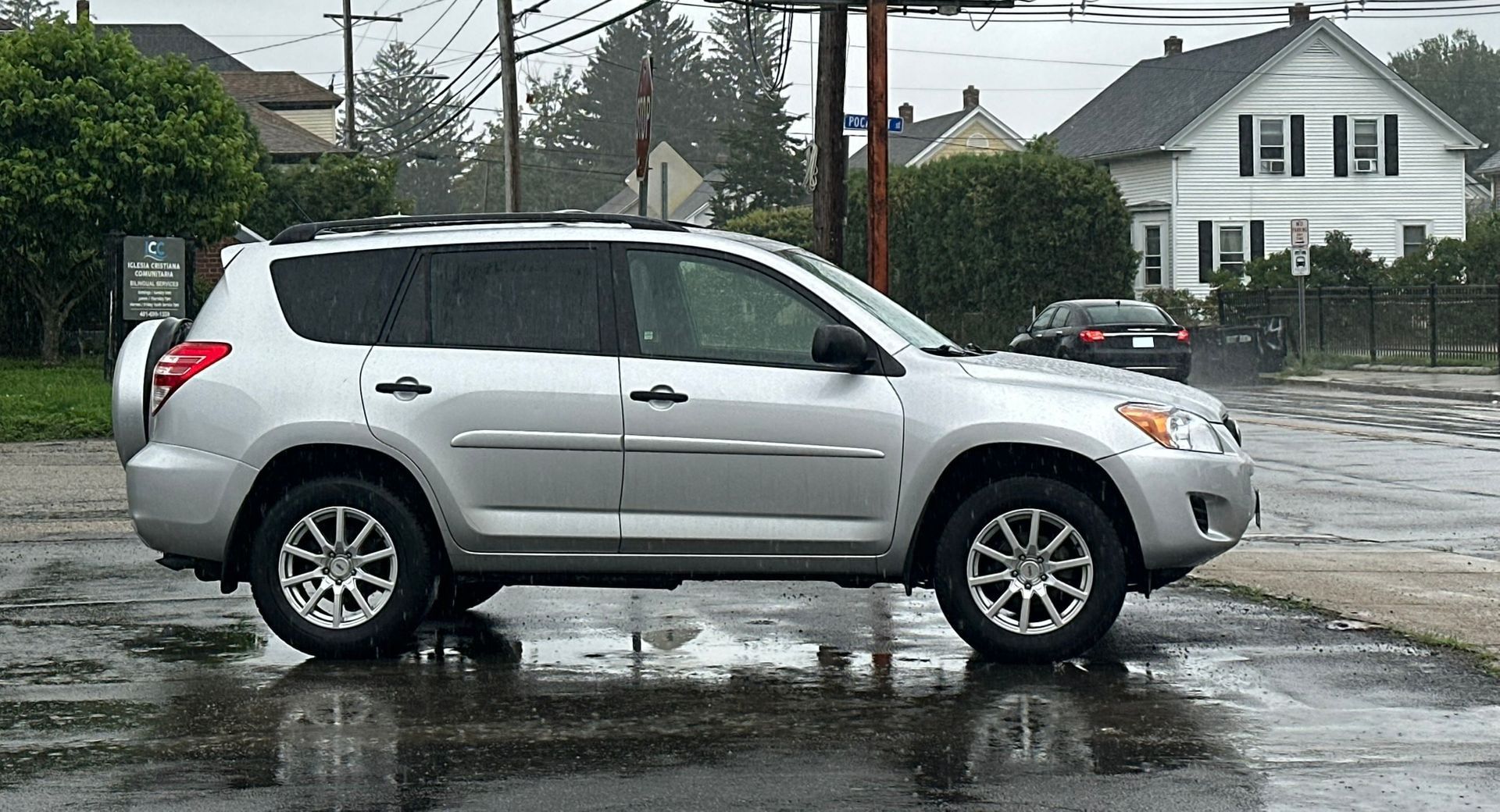 Silver SUV parked on a wet street in a rainy suburban neighborhood