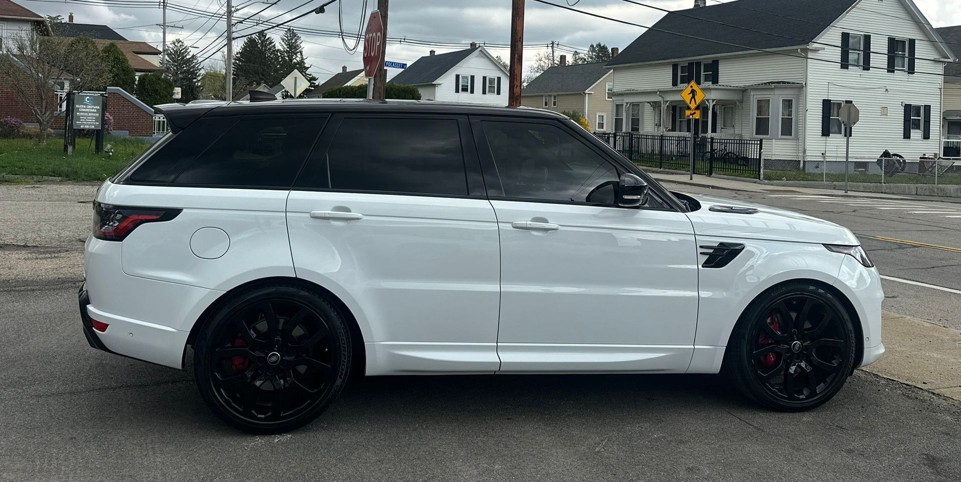 White SUV with black roof and wheels parked on a residential street on an overcast day