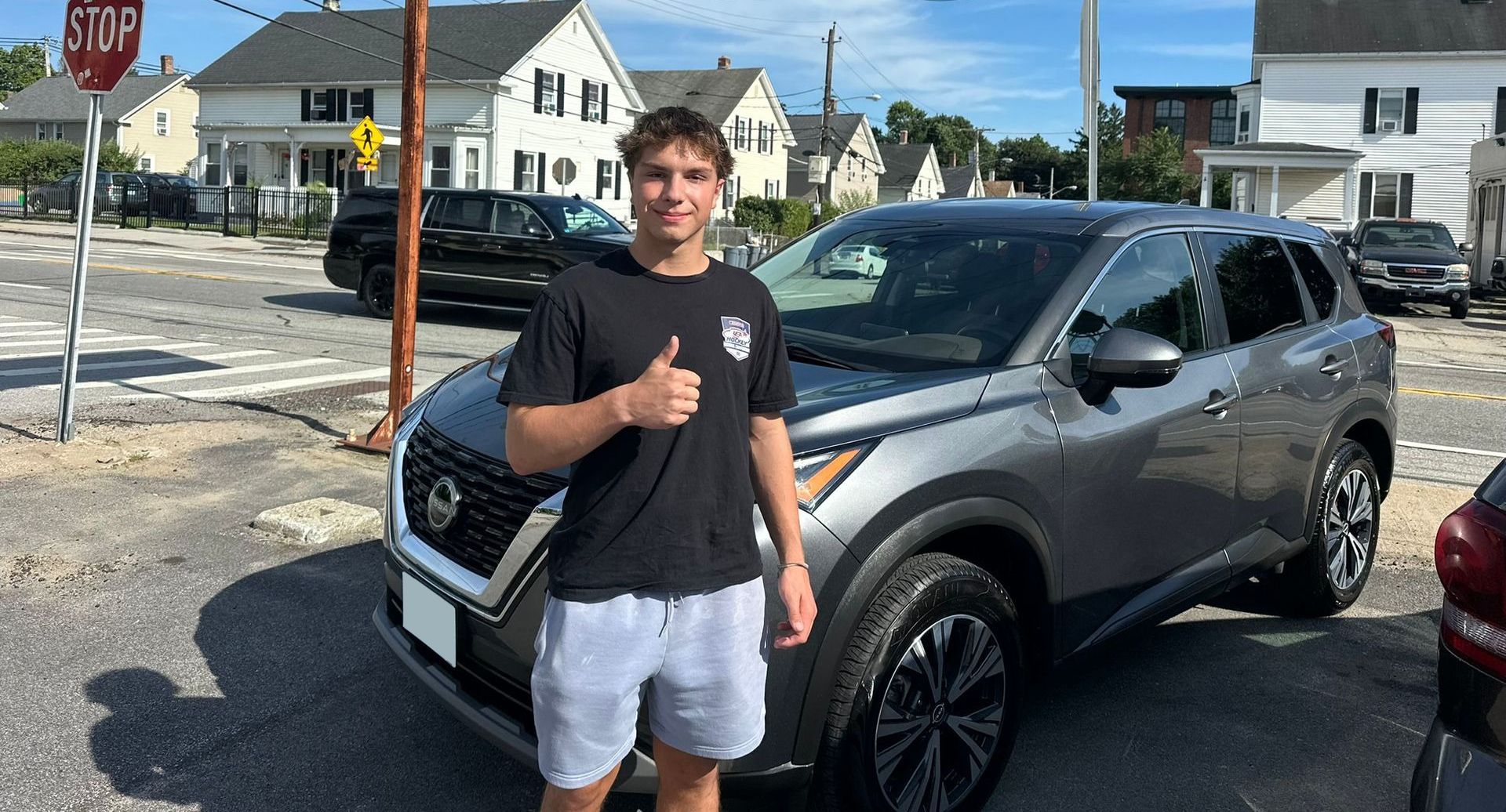 Person giving a thumbs-up beside a gray SUV in a parking lot.