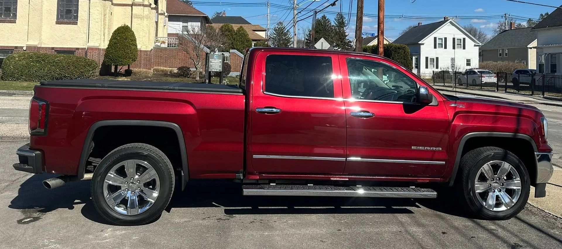 Red pickup truck parked on a street in front of houses on a sunny day