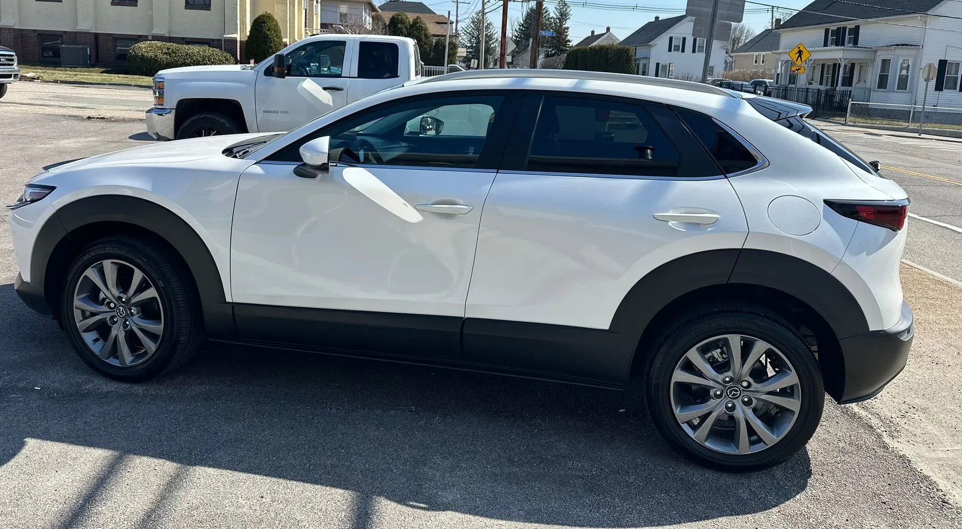 White SUV parked on a gravel lot in bright sunlight, side view