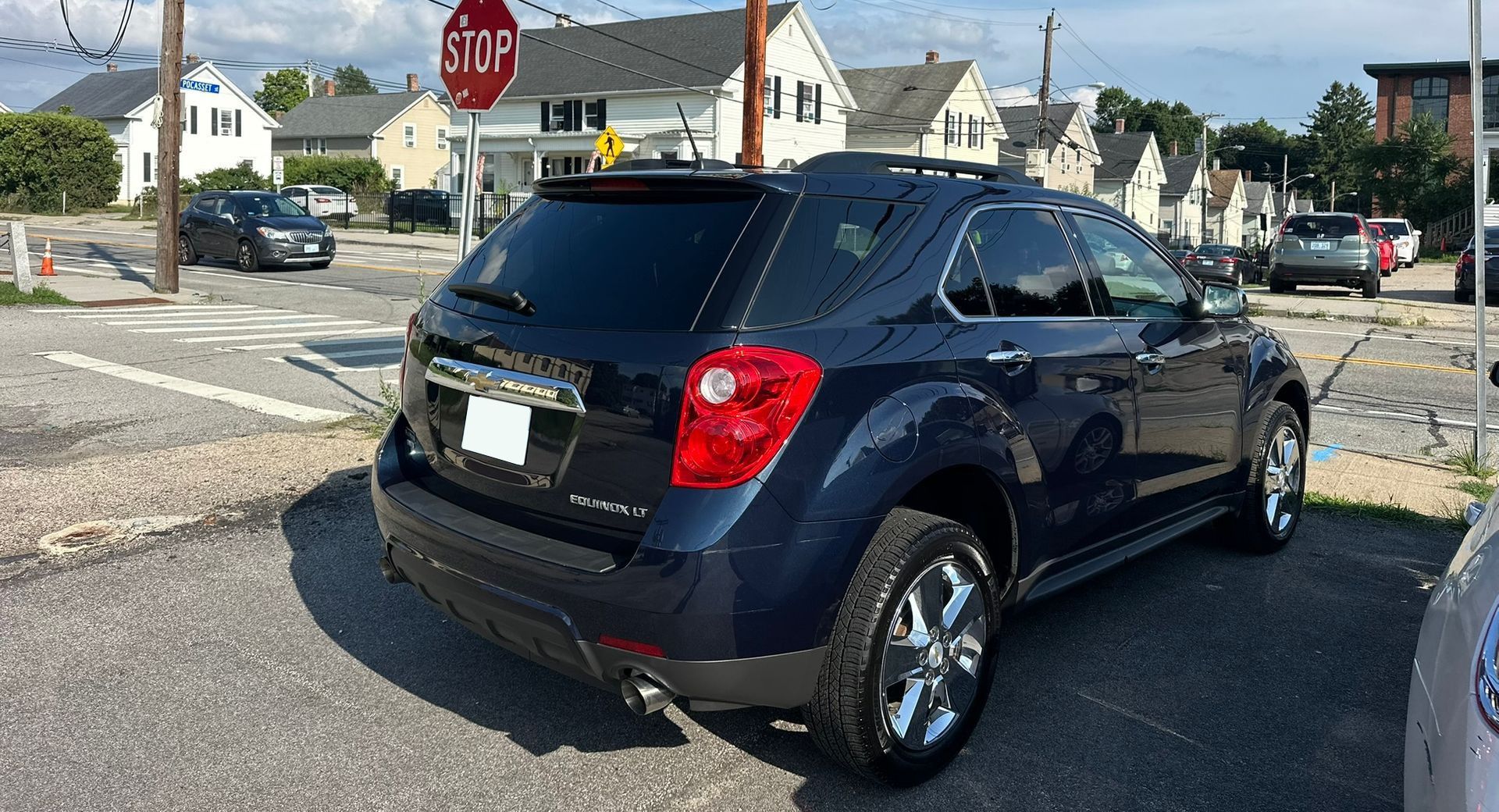 Dark blue SUV at a stop sign on a sunny suburban street corner
