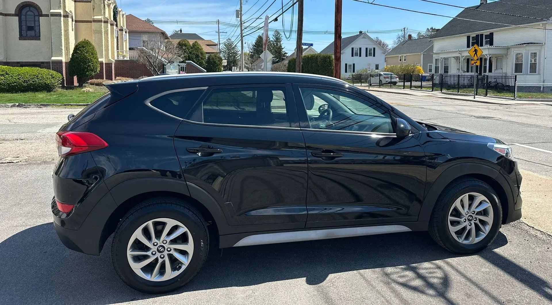 Black compact SUV parked on a sunny residential street with houses in the background