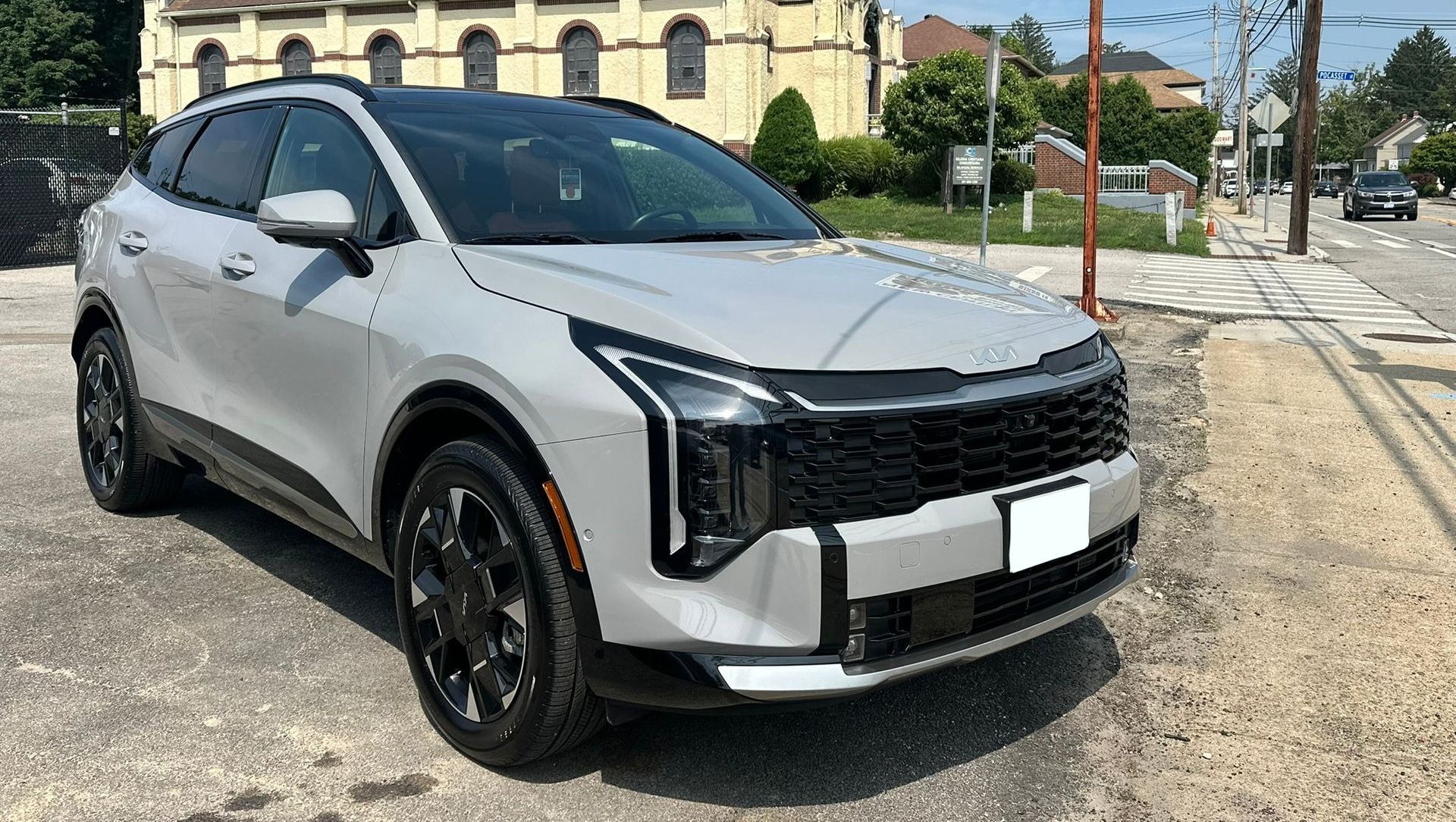 Silver SUV parked on a sunny street beside a stone building and tram tracks