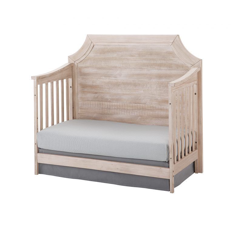 a wooden Remi clip crib with a mattress on it