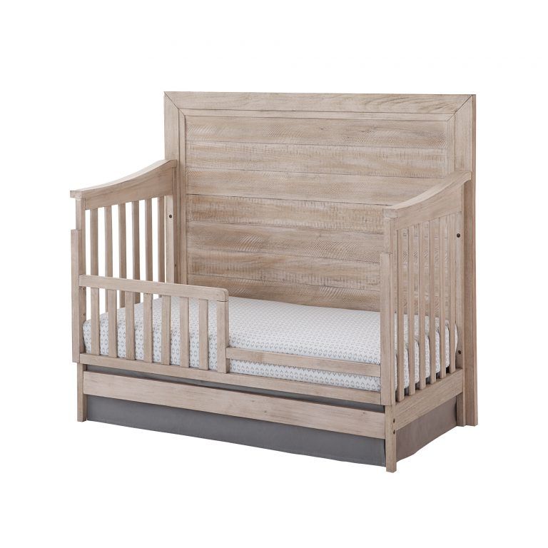 a wooden Remi flat crib with a white mattress on it