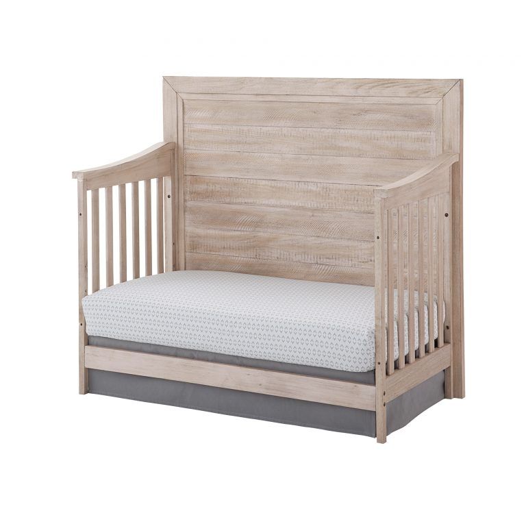 a wooden Remi flat crib with a white mattress on it