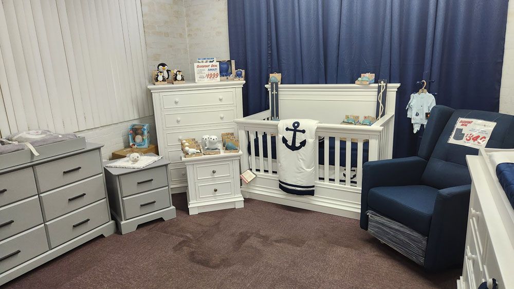 A baby room with a crib, chair, dresser, and nightstand