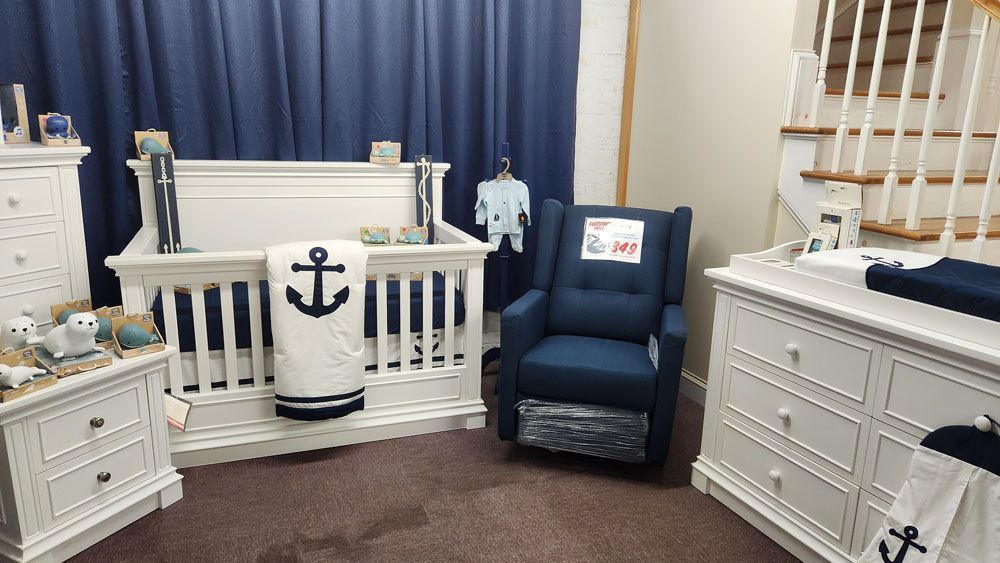 A baby room with a crib, chair, dresser, nightstand and stairs