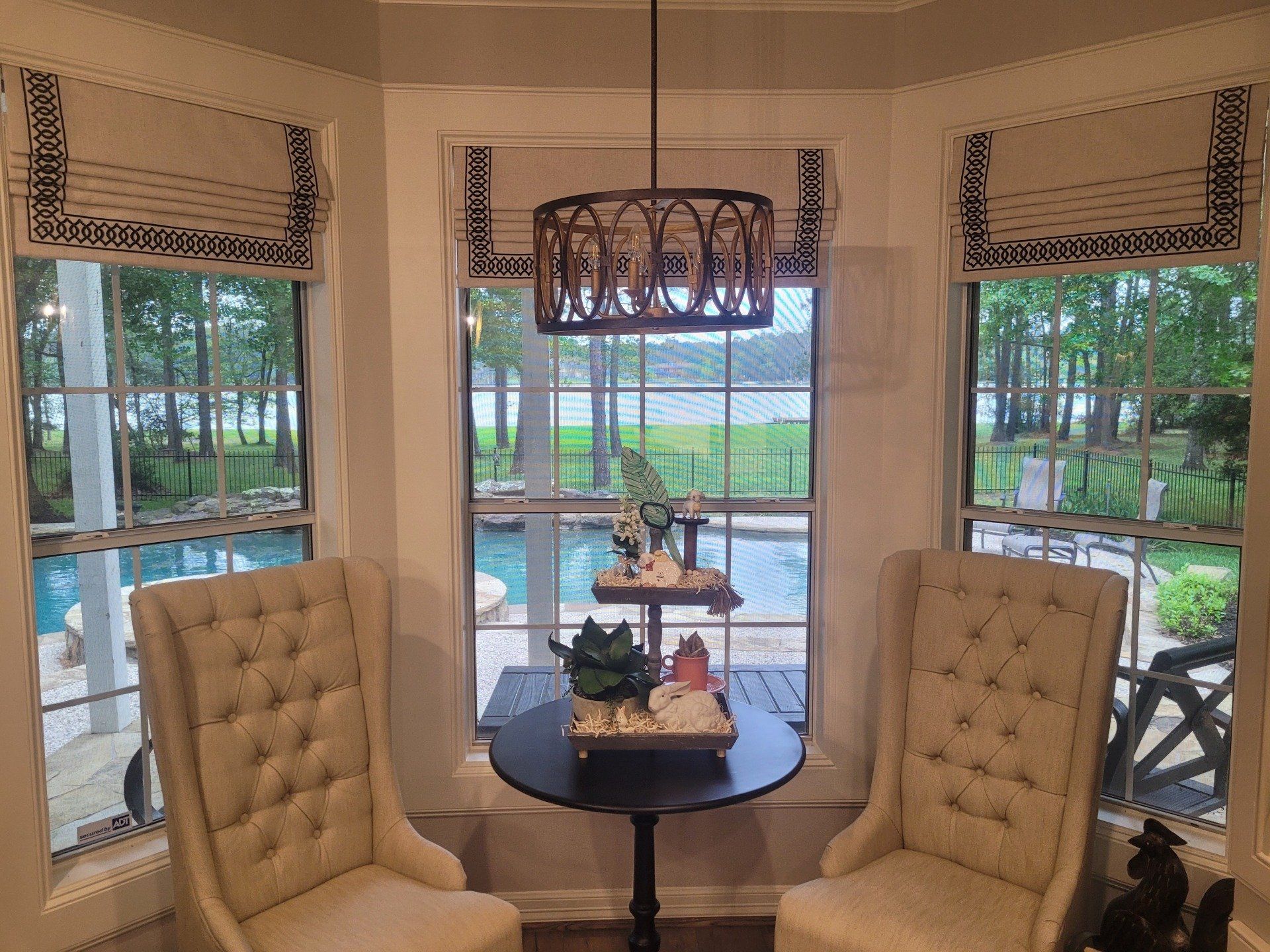 A living room with two chairs and a table with a view of a pool.