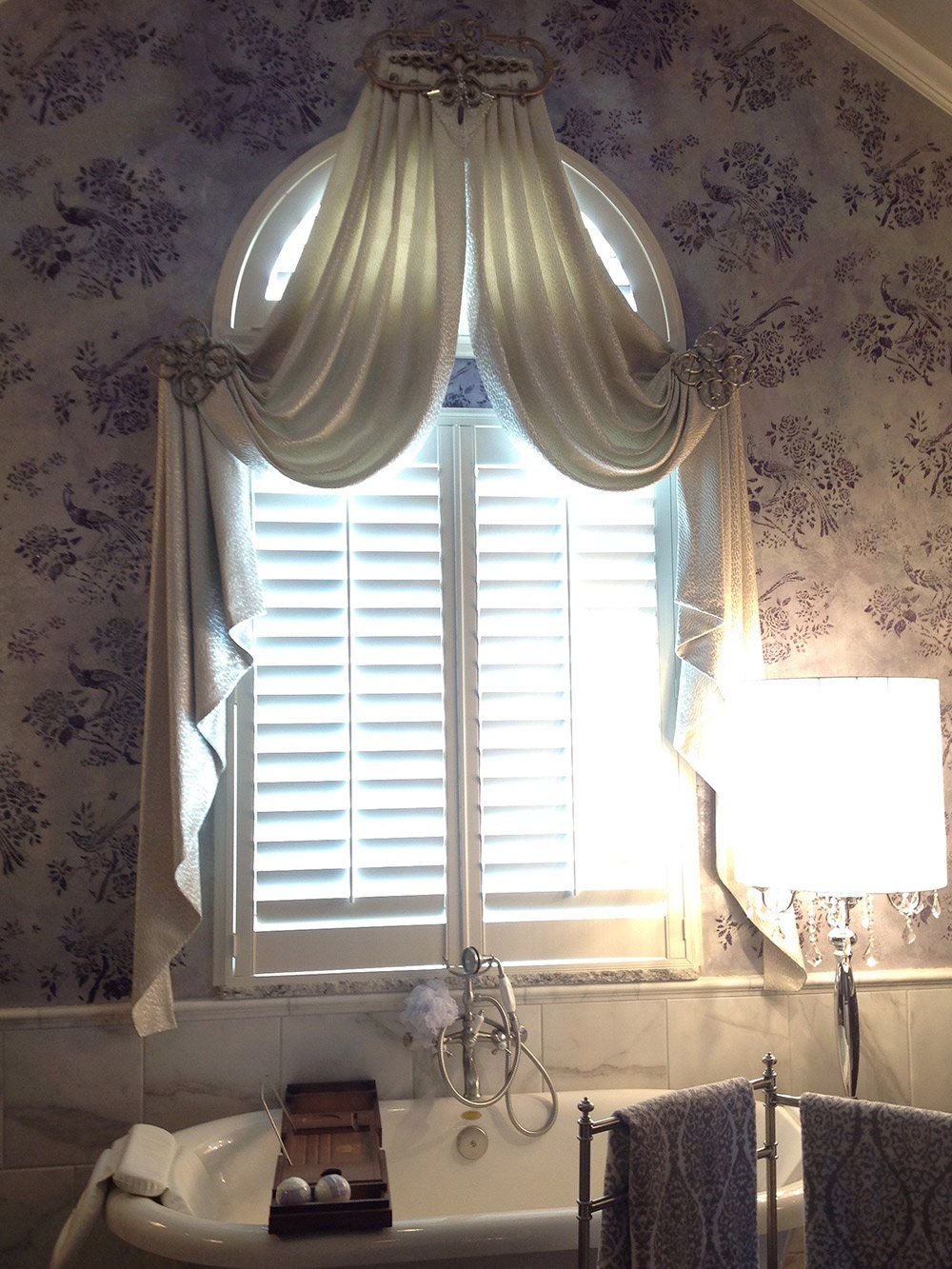 A bathroom with a tub and a window with shutters