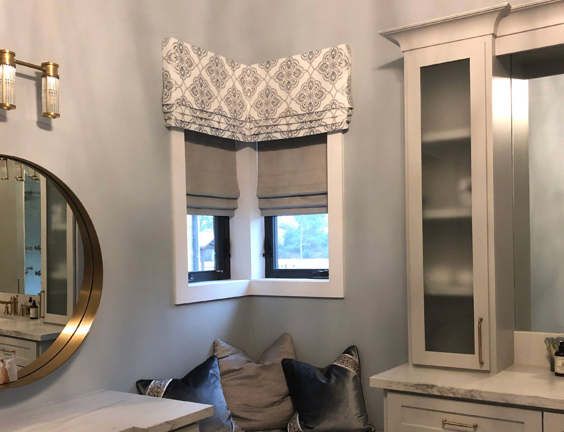 A bathroom with two windows and a round mirror