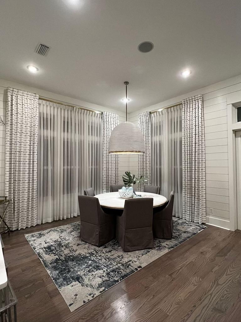 A dining room with a round table and chairs and a rug.