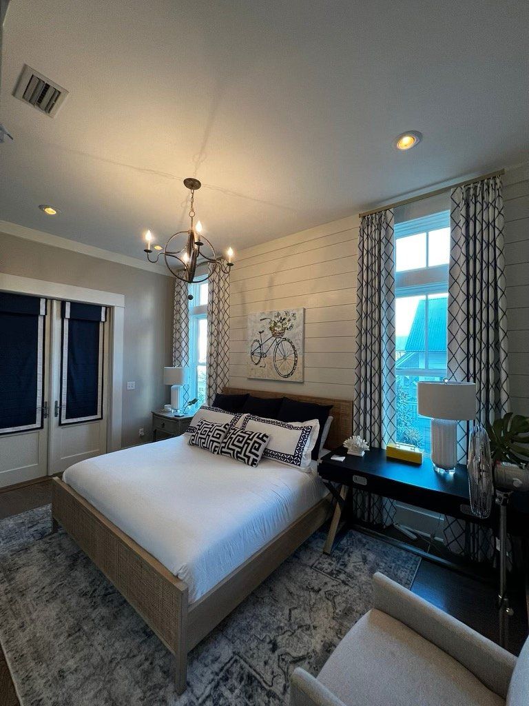 A bedroom with a king size bed , chair , desk and windows.