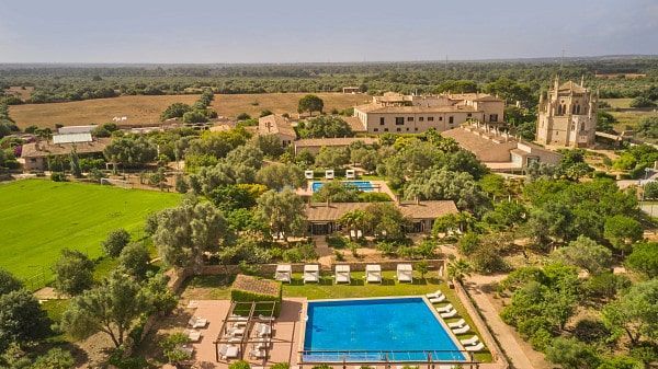 Aerial view of a Spanish estate with a pool, multiple buildings, and surrounding trees in a rural setting.