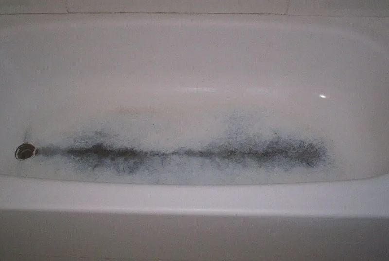 a bathtub with a lot of foam and black spots on it