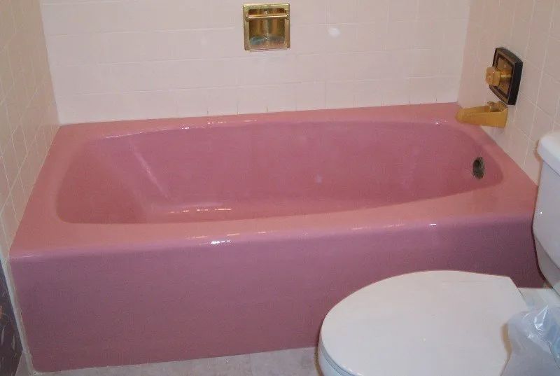 a pink bathtub is in a bathroom next to a toilet