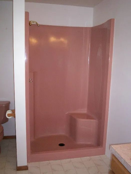 a pink shower stall in a bathroom next to a toilet