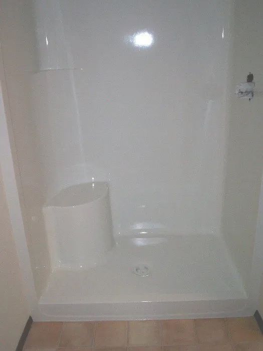 a white shower stall with a seat in a bathroom