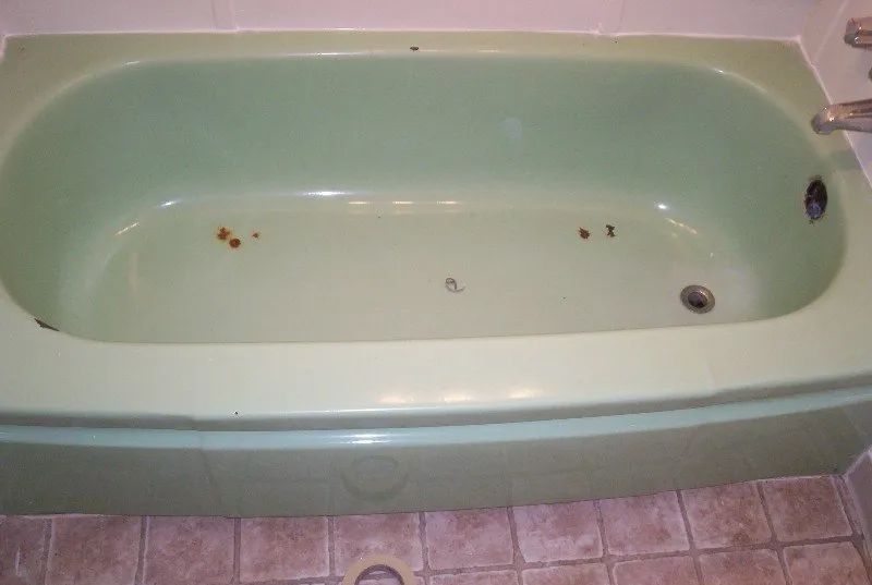 a green bathtub is sitting on a tiled floor in a bathroom