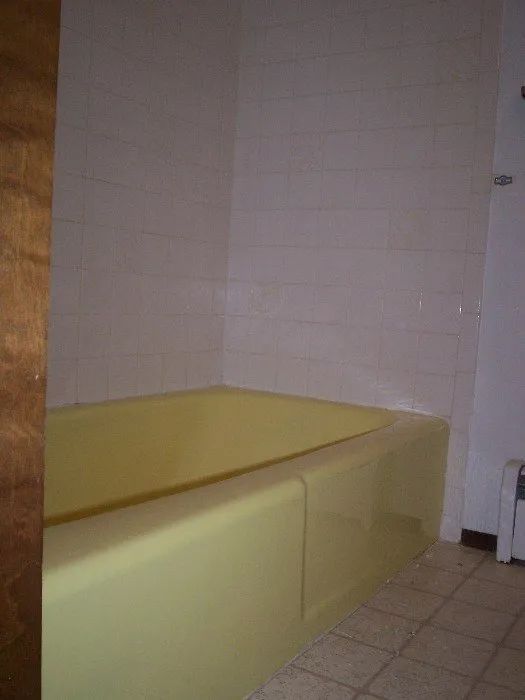 a bathroom with a yellow bathtub and white tiles