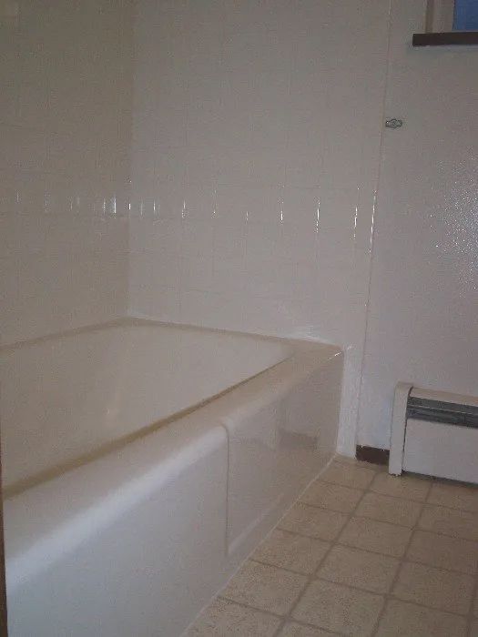 a bathroom with a bathtub and a radiator on the floor