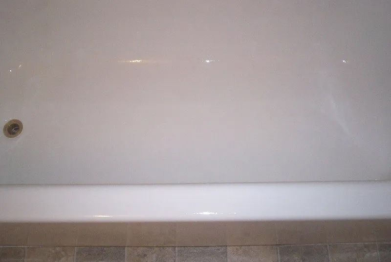 a white bathtub in a bathroom with a drain