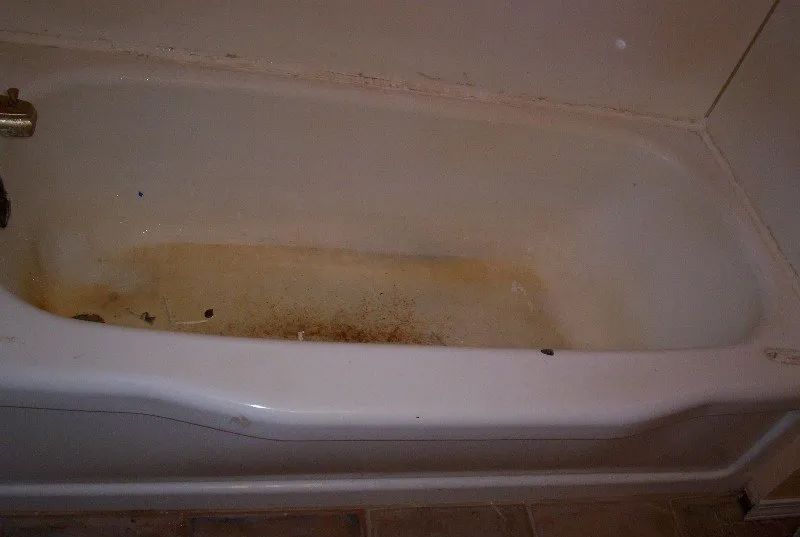 a dirty bathtub is sitting in a bathroom next to a wall