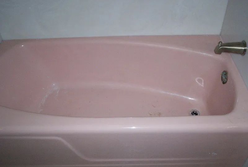 a pink bathtub is sitting in a bathroom next to a white wall