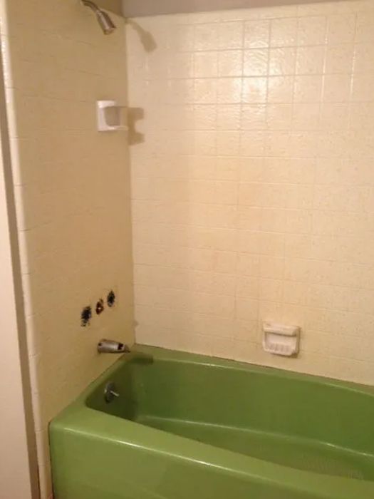 a green bathtub is in a bathroom next to a shower
