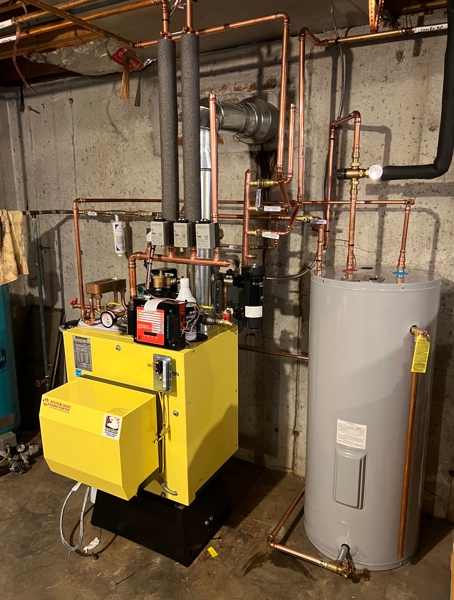 Yellow industrial boiler with copper pipes and a gray water heater in a basement utility room