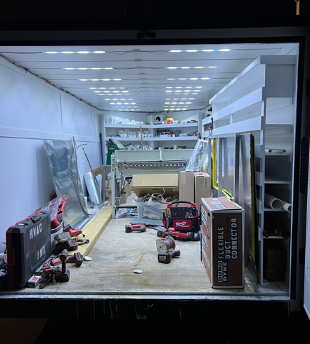 Cluttered white cargo truck interior with tools, boxes, and equipment being loaded or stored
