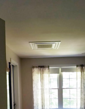 Interior room with ceiling vent and window dressed in sheer curtains letting in daylight