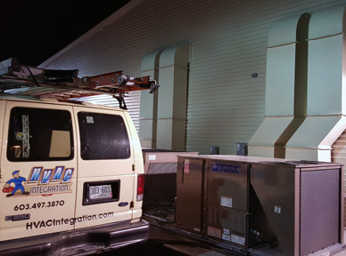 HVAC service van parked beside large rooftop units at night