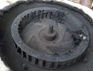 Dusty close-up of a metal turbine or fan wheel inside a circular housing