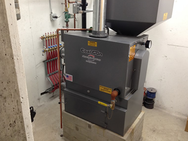 Gray furnace in a utility room with exposed red pipes and ductwork.