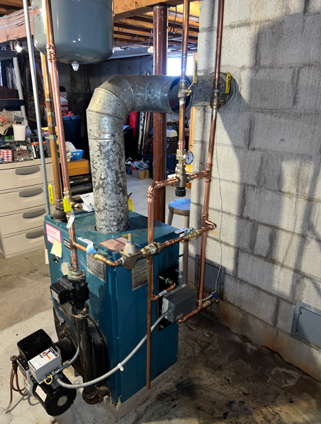 Basement HVAC furnace with insulated ducting and pipes beside a cinderblock wall.