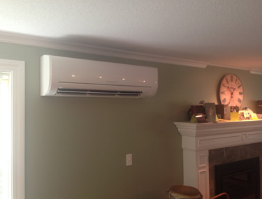 Wall-mounted white air conditioner above a fireplace in a beige living room