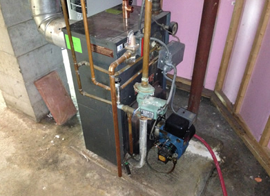 Basement furnace with copper pipes and a small pump beside it