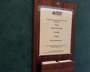 Framed plaque on a green wall with a white engraved award plate and wooden base.