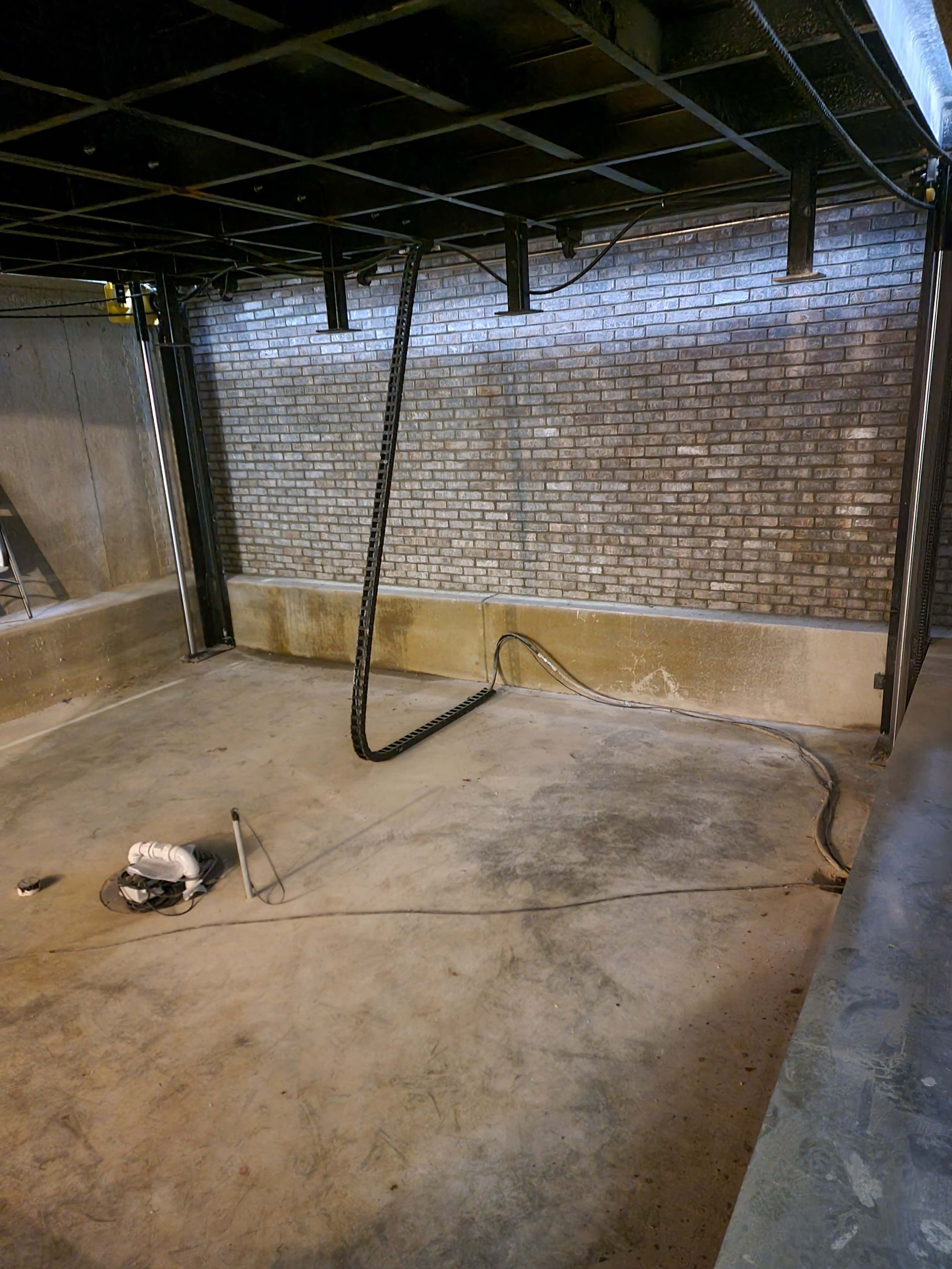 an empty room with a brick wall and a chain hanging from the ceiling .