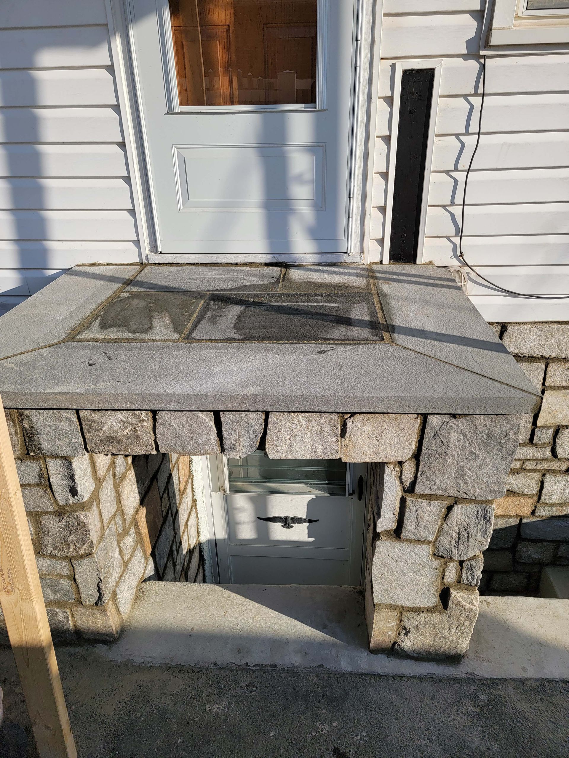 a stone porch with a window in the corner of a house .